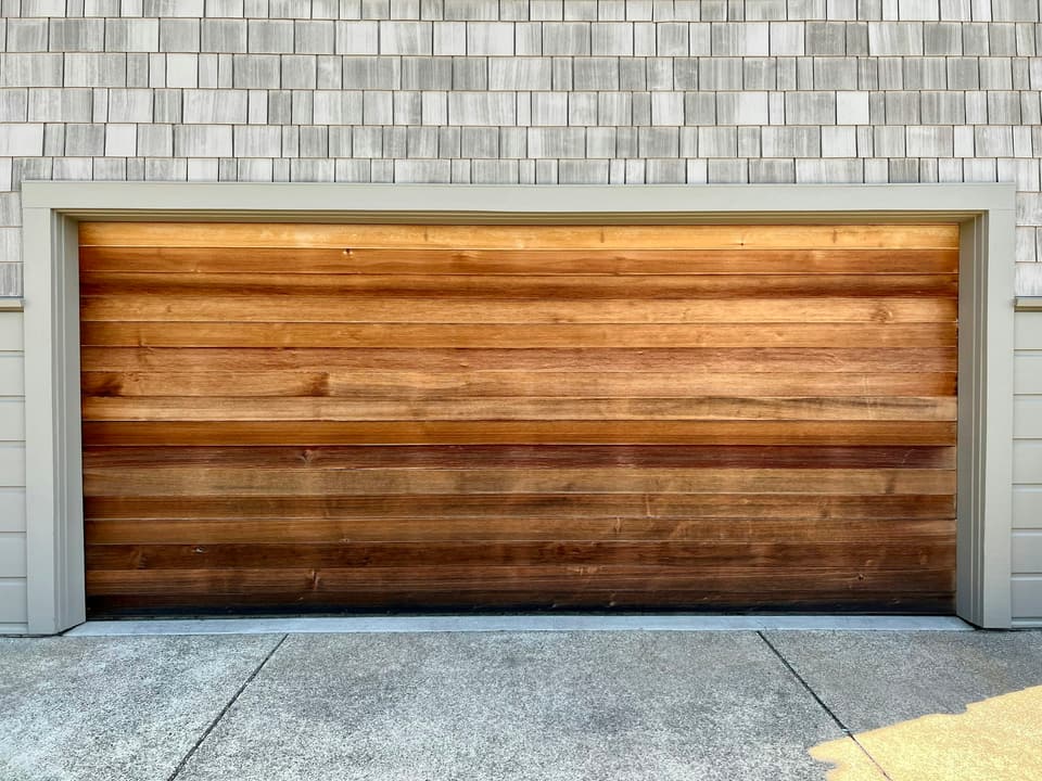 A cedar plank garage door set into shingle siding