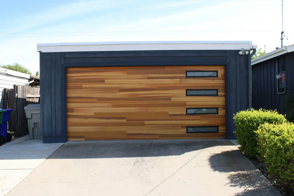 A modern wood-look garage door with a column of narrow windows